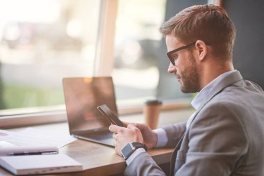 Kafe 'de internet üzerinden çalışan genç bir işadamı ya da erkek işadamının telefonunun yan görüntüsü