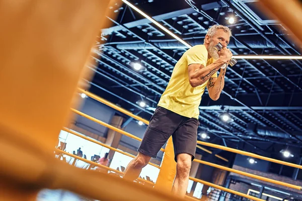 Körperlich aktiv bleiben. Sportlich reifer Mann in Sportbekleidung boxt, während er im Fitnessstudio auf dem Ring steht — Stockfoto