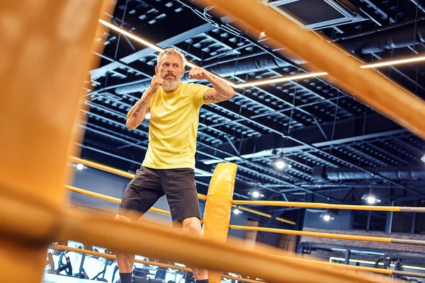 Sportlich reifer Mann in Sportbekleidung boxt, während er im Fitnessstudio auf dem Ring steht — Stockfoto
