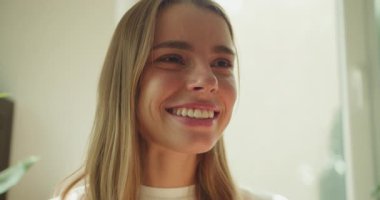 Dalgalı saçları olan neşeli bir kadın sıcak, sıcak ve mutlu bir ortamda lezzetli kahvesinin tadını çıkarırken ışıl ışıl parıldıyor.