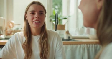 Isınma ve rahatlık saçan sıcak ve parlak bir mutfakta iki insan hoş bir sohbet ediyor.