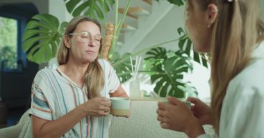 İki kadın, şık ve davetkar bir iç mekanda lezzetli bir kahvenin tadını çıkarırken sıcak ve ilgi çekici bir sohbeti paylaşıyor.