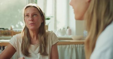 İki kadın sıcak, rahat bir mutfakta kahvelerini yudumlarken içten bir sohbete dalarlar.