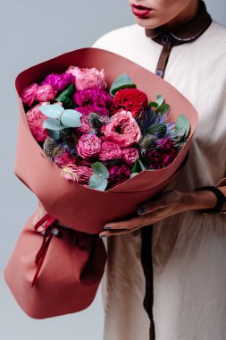 Terracotta Foamiran paketinde bir buket çiçek bir kadın çiçekçinin elinde. Gül, karanfil, eryngium, okaliptüs, celosia.