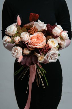 Çiçek buketi, arka planda bir çiçekçinin elinde. Rosa, cotinus, brunia, lagurus.