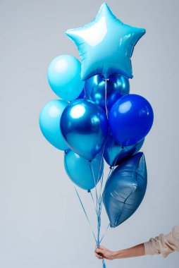 Koyu mavi, şeffaf helyum balonları ve beyaz arka planda bir kadının elinde iki safir yıldız..