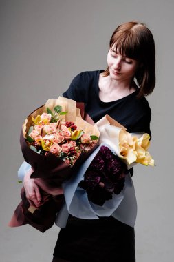 Genç bayan çiçekçinin portresi. Kahverengi saçlı, saç kesimli, çiçek buketli.