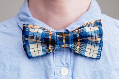 Mavi İskoç kafesi papyonu açık arkaplanda mavi gömlekli bir kadının boynunda..