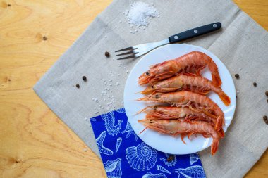 Beyaz tabakta dikenli ıstakoz. Gri bir masa örtüsünün üzerinde tahta bir masa.