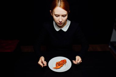 Beyaz bir tabakta kaynatılmış kerevit, siyah bir arka plan minimalizminde bıçak ve çatal.