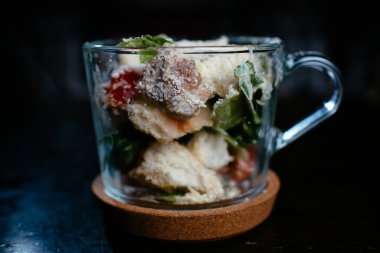 Siyah arkaplanda cam içinde Cesar salatası