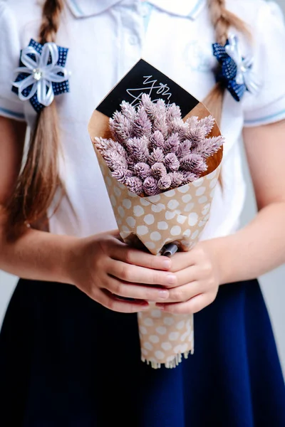 Phalaris 'li küçük bir buket, el işi kağıdına sarılı, saçı örgülü bir kızın elinde.