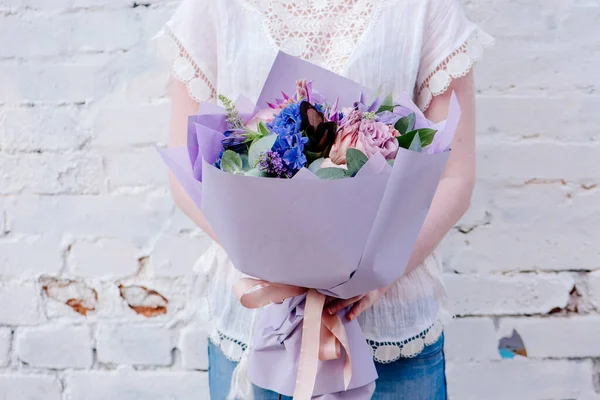 Bukiet Kwiatów Zapakowany Purpurowy Papier Rękach Kobiety Jasnym Tle Bukiet — Zdjęcie stockowe
