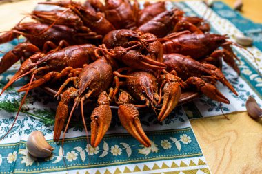 Ahşap bir masanın üzerinde mavi bir masa örtüsü üzerinde kaynatılmış kerevit.