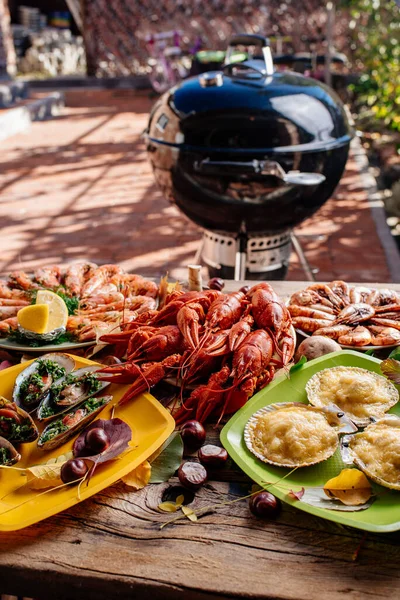 Kızarmış karides, fırında midye, haşlanmış kerevit ve istiridye ahşap masada peynirin altında pişirilmiş sonbahar yaprakları, mantarlar, kestaneler ve bbq