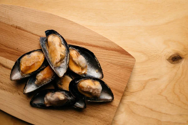 Tahta bir masanın üzerinde, kabuklu midyeler.