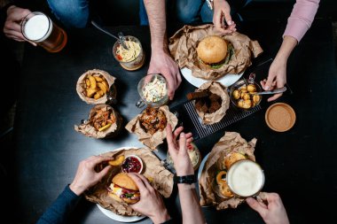 Arkadaşlarla bira partisi için harika bir menü. Hamburger, sandviç, salata, patates kızartması, kızarmış ekmek, köfte, kızarmış karides, makarna, siyah masada kızarmış tavuk.