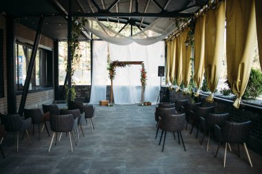 Düğün töreni için ahşap kemer, süslü kumaş, çiçekler ve yeşillik.