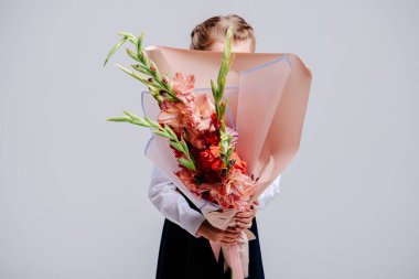 Bir buket gladiolus, şeftali kağıda sarılmış bir kızın ellerinde..