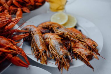 Kaynamış kerevit ve kızarmış ıstakoz beyaz bir tabakta hafif bir arka planda limonla.