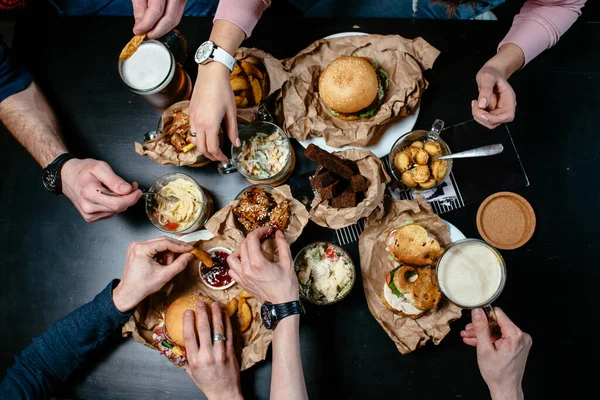 Arkadaşlarla bira partisi için harika bir menü. Hamburger, sandviç, salata, patates kızartması, kızarmış ekmek, köfte, kızarmış karides, makarna, siyah masada kızarmış tavuk.