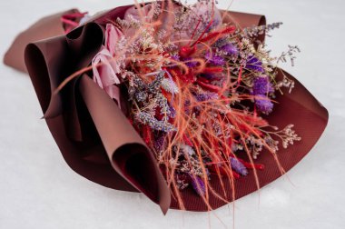 Güzel bir demet lavanta, limonyum ve tüy tüyü beyaz kar üzerinde kahverengi ambalajlı.