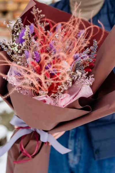Güzel bir demet lavanta, limonyum ve tüy çimeni kahverengi ambalajlı bir kadının ellerinde.
