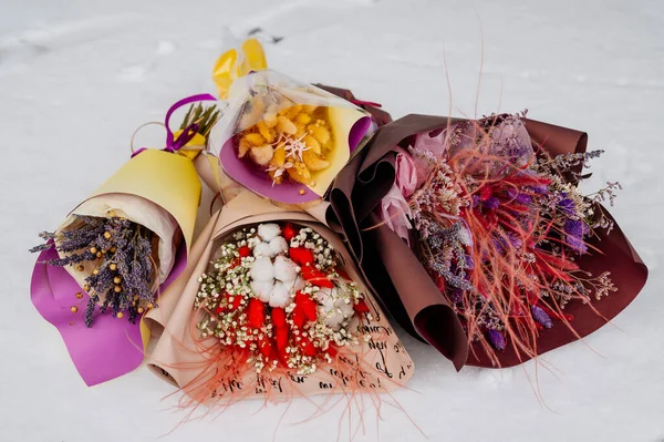 Beyaz kar üzerinde çeşitli paketler halinde kurutulmuş güzel bitkiler.