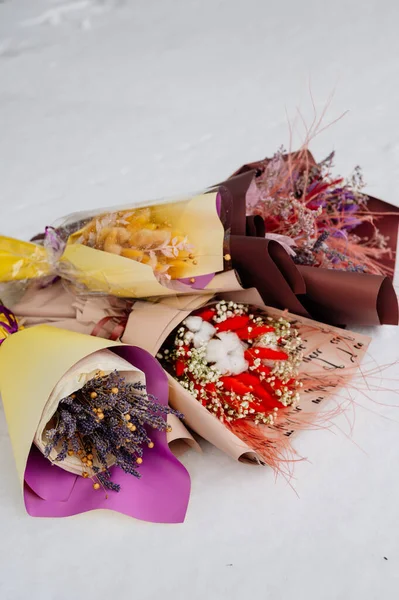 Beyaz kar üzerinde çeşitli paketler halinde kurutulmuş güzel bitkiler.