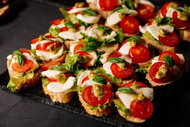 Mozzarella, domates ve pesto soslu siyah masa.