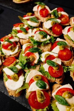 Mozzarella, domates ve pesto soslu siyah masa.