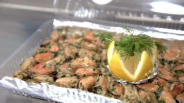 Kabuksuz kızarmış midye, dilimlenmiş limon ve dereotlu, masada plastik kutuda. HD