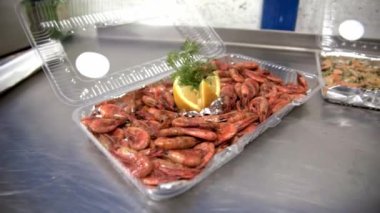 Kabuksuz kızarmış karides ve midye dilimlenmiş limon ve dereotlu masanda plastik kutu. HD