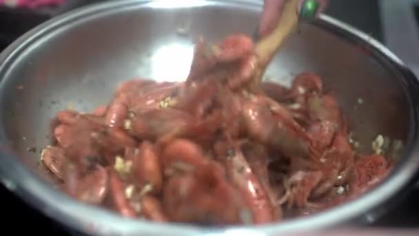Krevety se smaží na pánvi v olivovém oleji se sójovou omáčkou a česnekem. Kuchař míchá krevety s špachtlí. HD — Stock video
