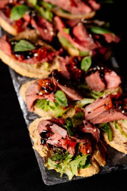 Fırında sığır eti, roka ve balzamik soslu siyah masa.