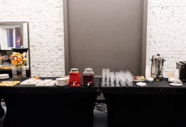 Beyaz tuğla duvar arka planında etkinlik için çiçeklerle servis büfesi