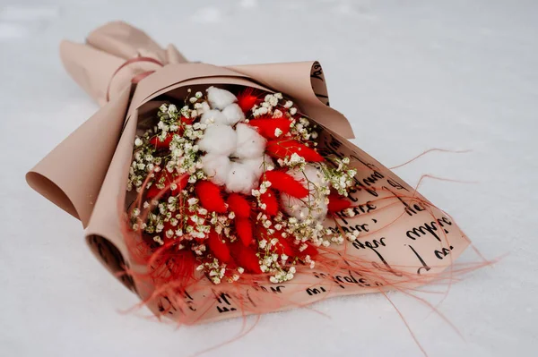 Güzel bir buket pamuk-bitki, laguru, tüylü ot ve beyaz kar üzerinde pembe ambalajlı çingene.