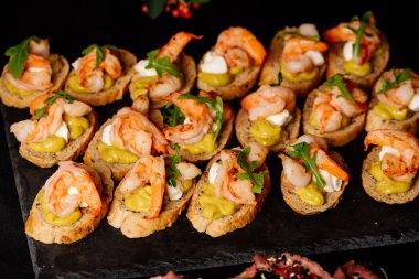 Kızarmış karides, roka ve peynir soslu siyah masa.