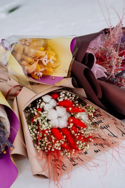 Beyaz kar üzerinde çeşitli paketler halinde kurutulmuş güzel bitkiler.