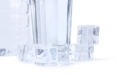Beyaz arka planda izole edilmiş bir şişe su, bir bardak ve buz küpleri. Buzlu saf içme suyu.