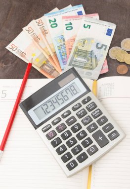Hesap makineli banknotlar ve paralar. Avro banknotları ve ahşap arka planda not defteri. Vergi, kâr ve maliyet için fotoğraf. 50 Euro, 20 Euro, 10 Euro. Para ve finans