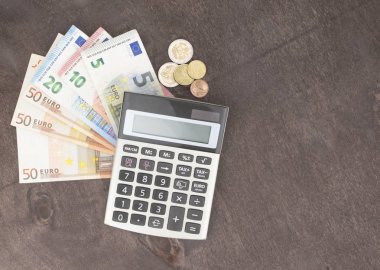 Hesap makineli banknotlar ve paralar. Tahta arka planda Euro banknotları. Vergi, kâr ve maliyet için fotoğraf. 50 Euro, 20 Euro, 10 Euro. Para ve finans