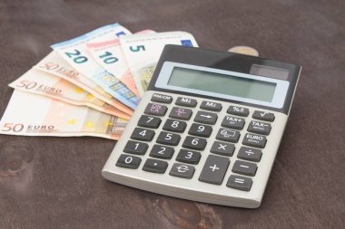 Hesap makineli banknotlar ve paralar. Tahta arka planda Euro banknotları. Vergi, kâr ve maliyet için fotoğraf. 50 Euro, 20 Euro, 10 Euro. Para ve finans