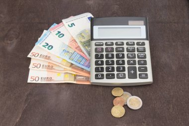 Hesap makineli banknotlar ve paralar. Tahta arka planda Euro banknotları. Vergi, kâr ve maliyet için fotoğraf. 50 Euro, 20 Euro, 10 Euro. Para ve finans