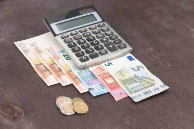 Hesap makineli banknotlar ve paralar. Tahta arka planda Euro banknotları. Vergi, kâr ve maliyet için fotoğraf. 50 Euro, 20 Euro, 10 Euro. Para ve finans