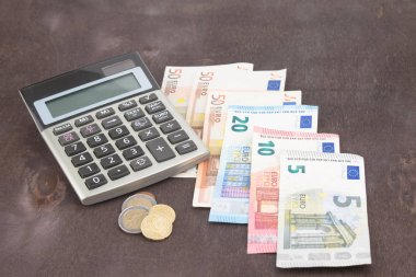 Hesap makineli banknotlar ve paralar. Tahta arka planda Euro banknotları. Vergi, kâr ve maliyet için fotoğraf. 50 Euro, 20 Euro, 10 Euro. Para ve finans