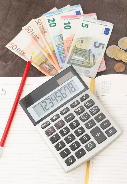 Hesap makineli banknotlar ve paralar. Avro banknotları ve ahşap arka planda not defteri. Vergi, kâr ve maliyet için fotoğraf. 50 Euro, 20 Euro, 10 Euro. Para ve finans