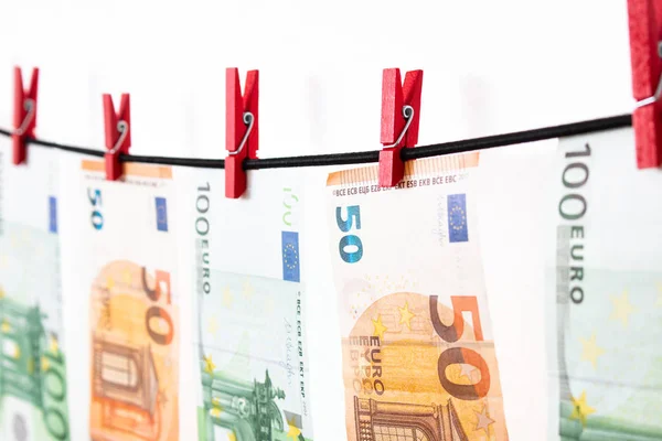 Beyaz arka planda çamaşır ipine asılı Euro banknotları. Kırmızı mandallı Euro parası. Para aklama Euro 'su kurumaya bırakıldı. İzole edilmiş euro parası.