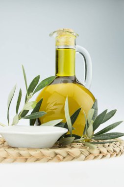 Zeytin yağı şişesi ve zeytin dalı uzatılmış kase. Bakir zeytinyağı. Doğal zeytinyağı, sağlıklı yiyecekler. Doğal Akdeniz yiyeceği. Ekmek batırma.
