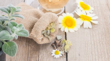 Papatya çayı, papatya çayı ve kırsal ahşap arka planda bitkilerle dolu bir çanta. Bitki çayı çiçekleri ve dittany..